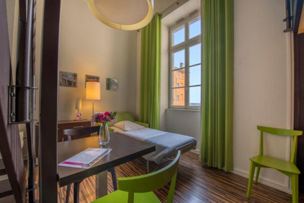 a room with a desk and green curtains and a table and chairs at Résidence Villemanzy in Lyon