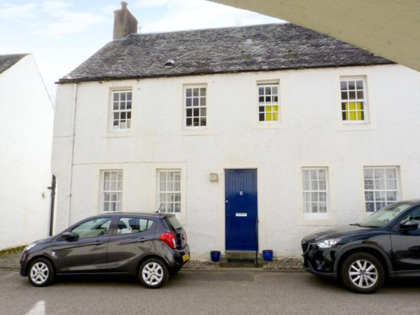 dos autos estacionados frente a una casa blanca en 8 Cathedral Street en Dunkeld