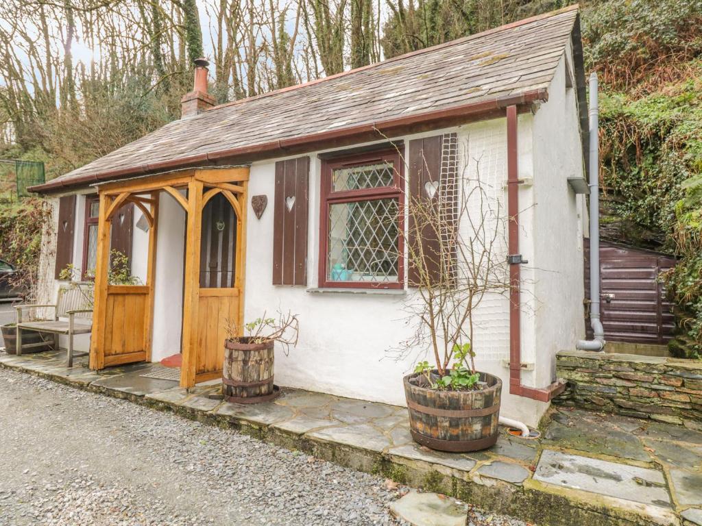 ein kleines weißes Cottage mit einer Holztür in der Unterkunft Coachman's in Forrabury
