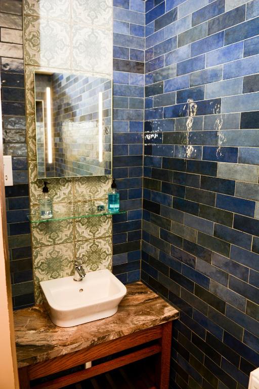a blue tiled bathroom with a sink and a mirror at Plough Inn in Morpeth