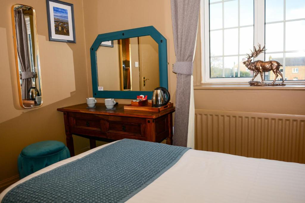 a bedroom with a bed and a dresser and a mirror at Plough Inn in Morpeth