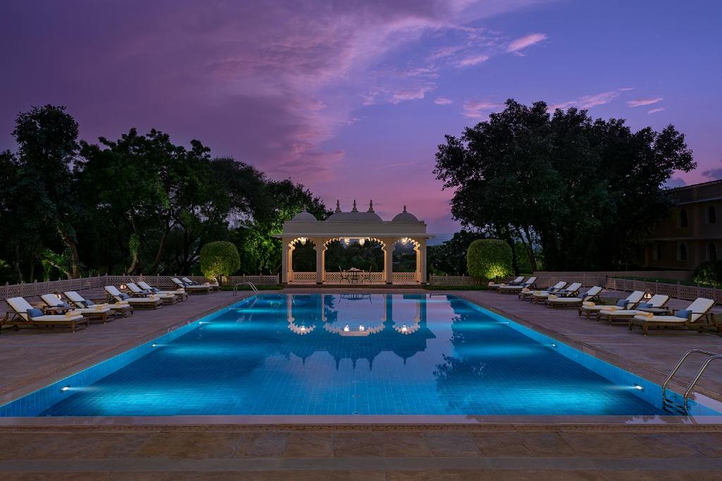 a swimming pool with a gazebo and chairs at Trident Udaipur in Udaipur