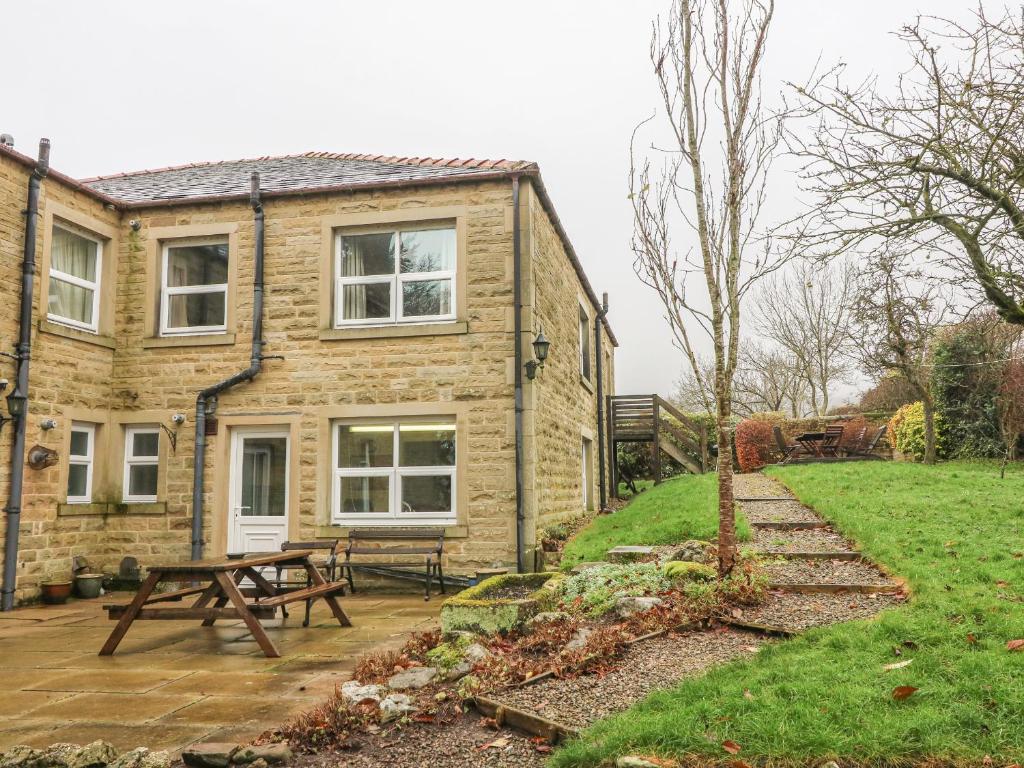 a stone house with a picnic table and a bench at Laurel Bank Cottage in Embsay