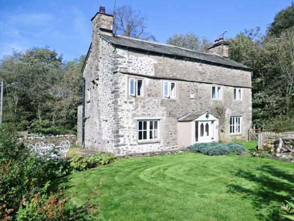 an old stone house with a yard in front of it at Fleshbeck Cottage in Barbon