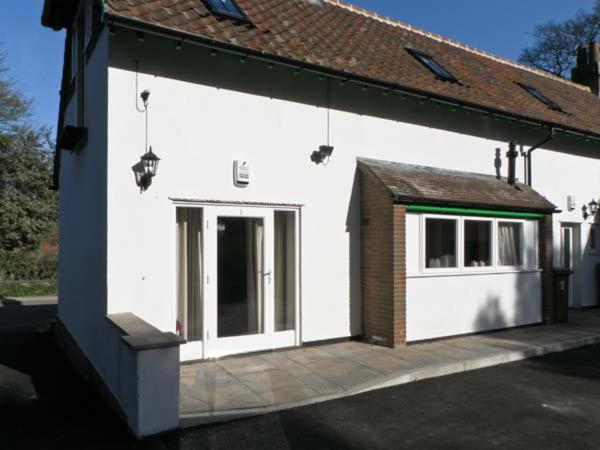 a white building with a door and a window at No 1 Low Hall Cottages in Scalby