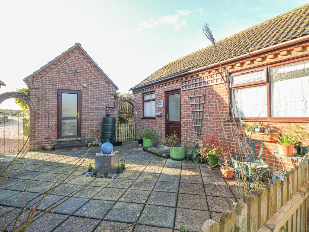 a brick house with a fence and a fire hydrant at Robyn's Nest in Sharrington