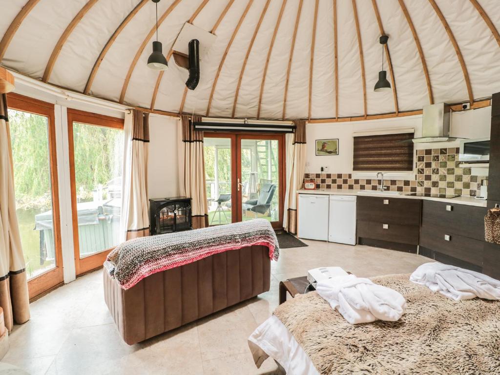 a yurt with two beds and a kitchen with windows at Island Yurt in Beckford