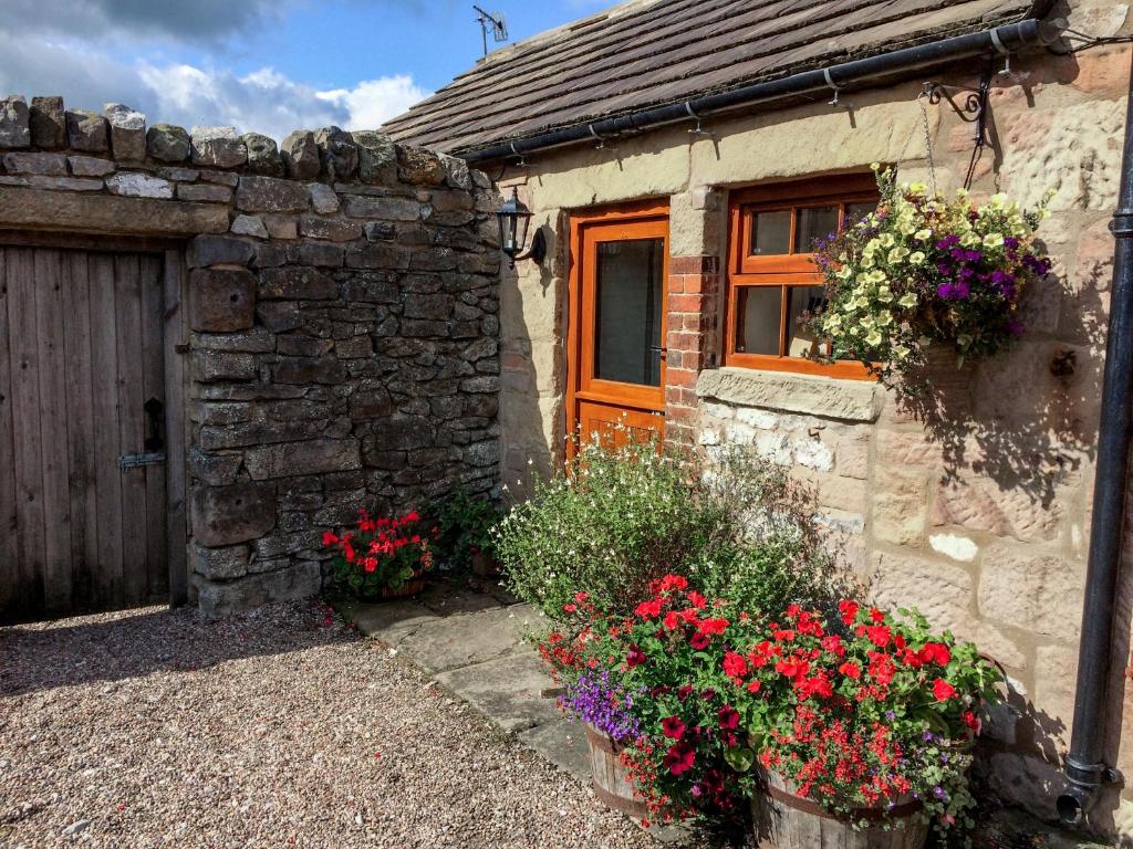 a stone house with flowers in front of it at The Cow Shed in Stanton in Peak