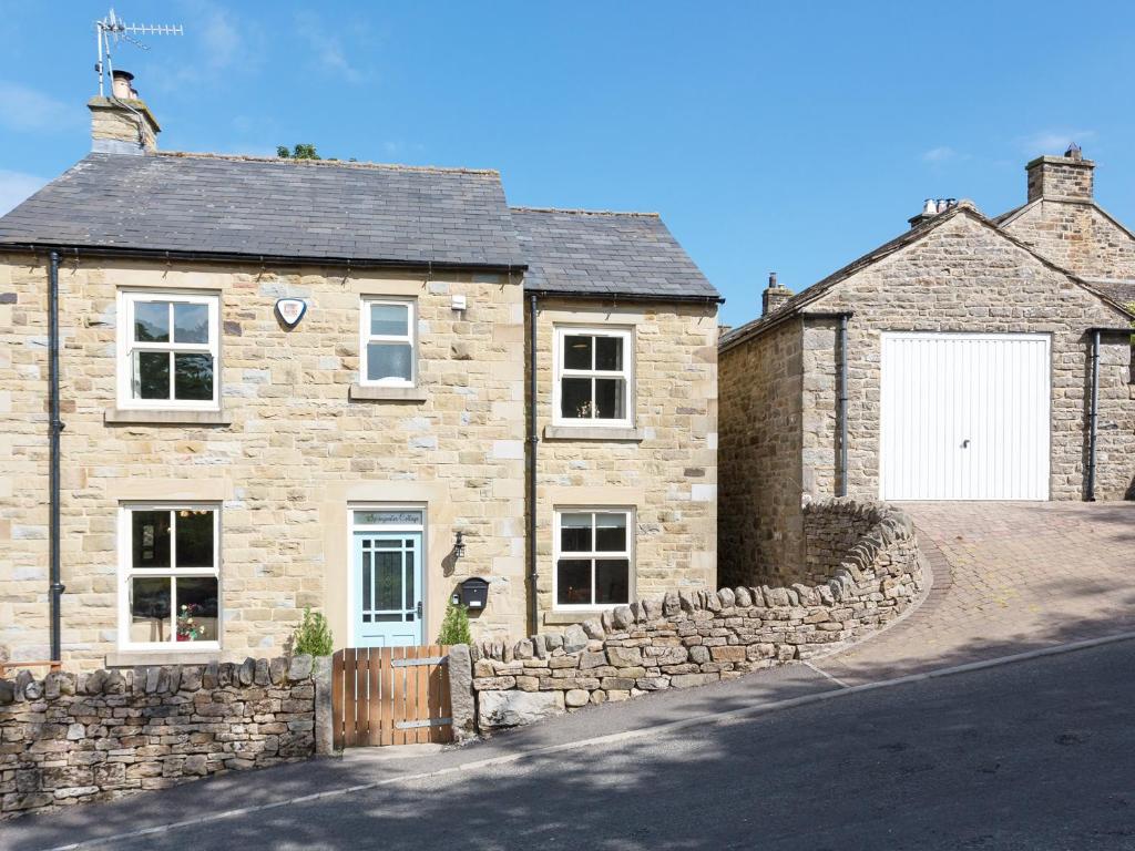a stone house with a stone wall and a white garage at 1 Springwater View in Mickleton