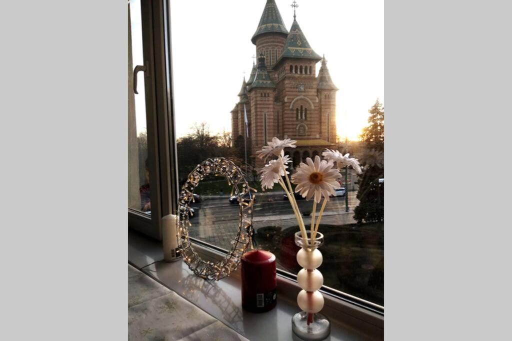 a window with a vase with flowers and a castle at Ultracentral Cathedral Apartament Timisoara in Timişoara
