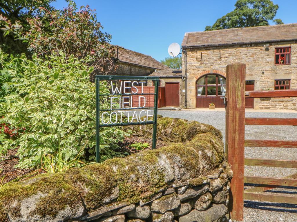 a sign in front of a building with a gate at Westfield Cottage in Mickleton