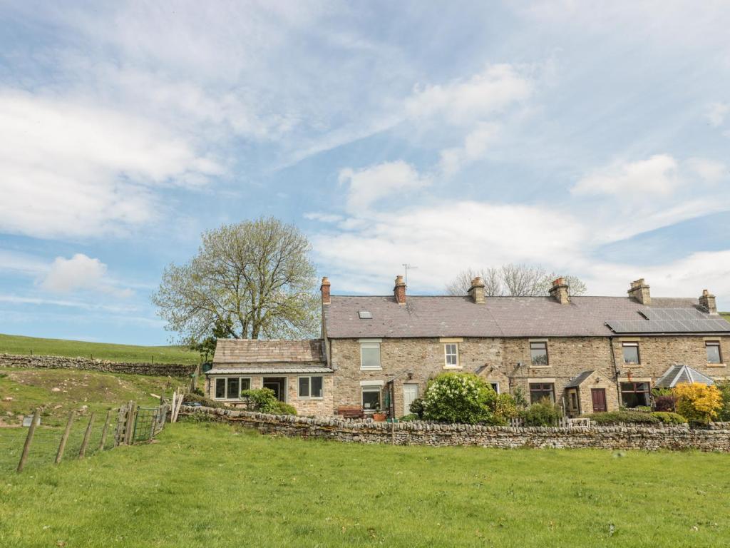 una grande casa in pietra in un campo con una recinzione di Hoodgill Barn a Newbiggin