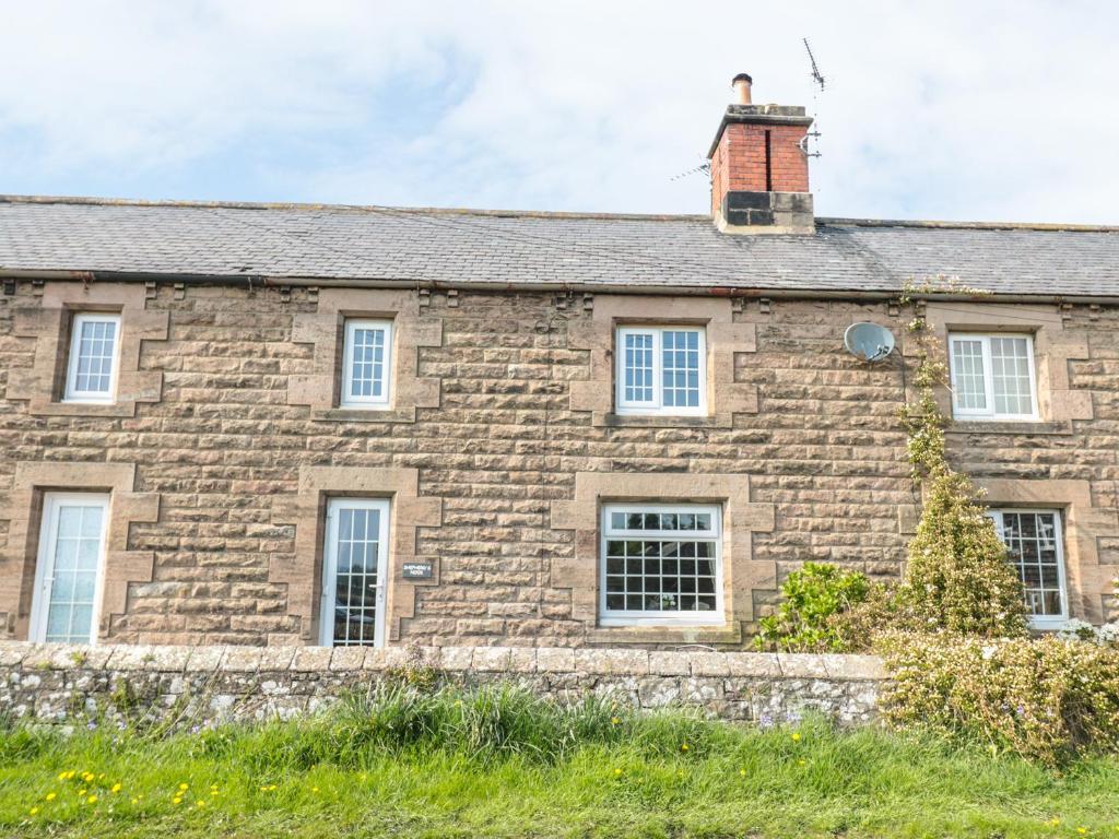 una antigua casa de piedra con un edificio de ladrillo en Shepherds Nook en North Charlton