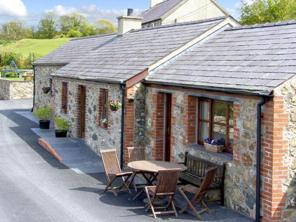 a small brick house with a table and chairs at Penrallt Cottage in Y Felinheli