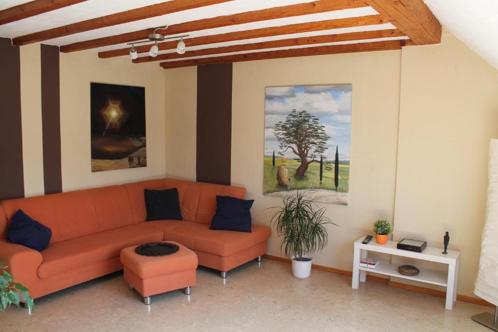 a living room with an orange couch and a table at Ferienwohnung im Galerie-Haus in Urbar