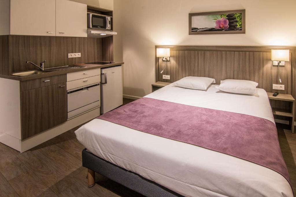 a bedroom with a large bed and a kitchen at Tulip Inn Thionville Residences in Thionville