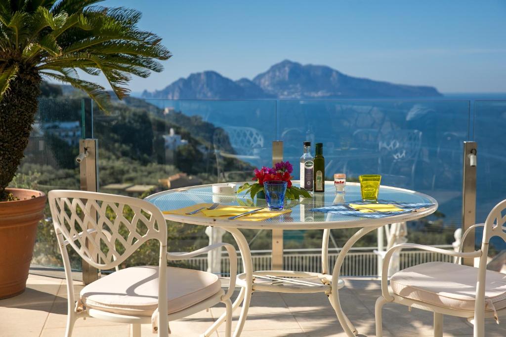y balcón con mesa de cristal y sillas. en Hotel & Spa Bellavista Francischiello en Massa Lubrense