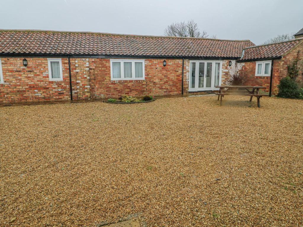 a brick house with a bench in front of it at Peardrop Cottage in Saltfleetby Saint Peter