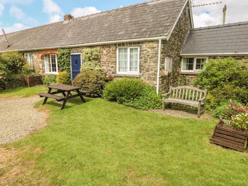 una casa con una mesa de picnic y un banco en el patio en Eynons Cottage, en Roch