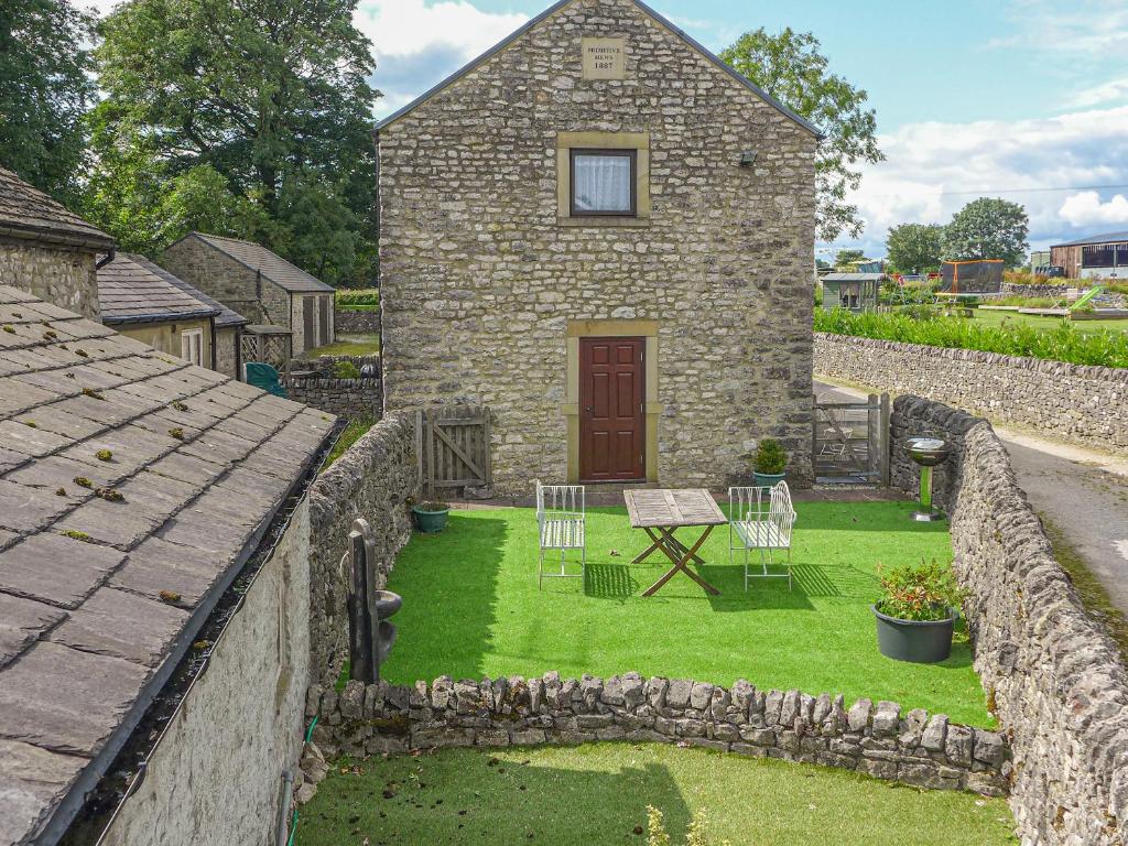 a stone house with a yard with a table and chairs at 3 Primitive Mews in Chelmorton