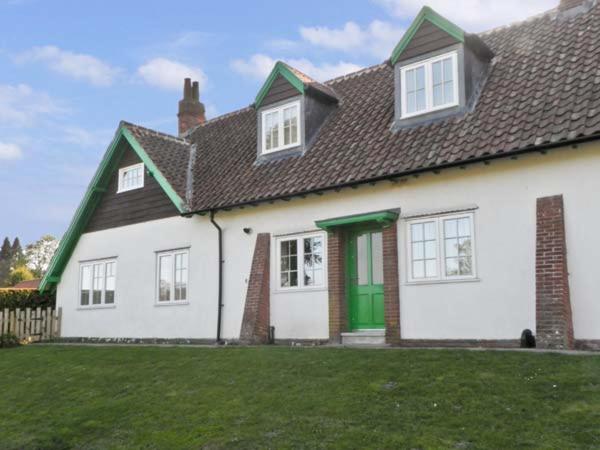 a white house with a green door and a yard at No 2 Low Hall Cottages in Scalby