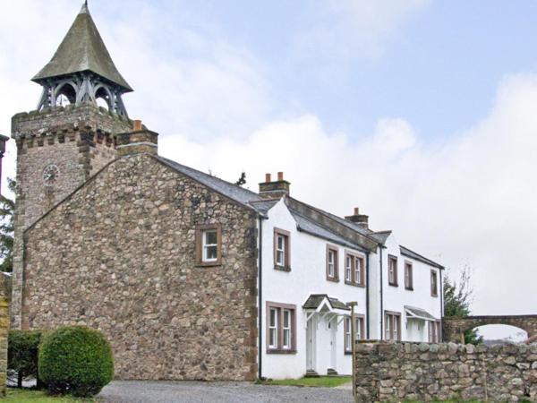 un grande edificio in pietra con una torre sopra di William Court Cottage a Santon Bridge