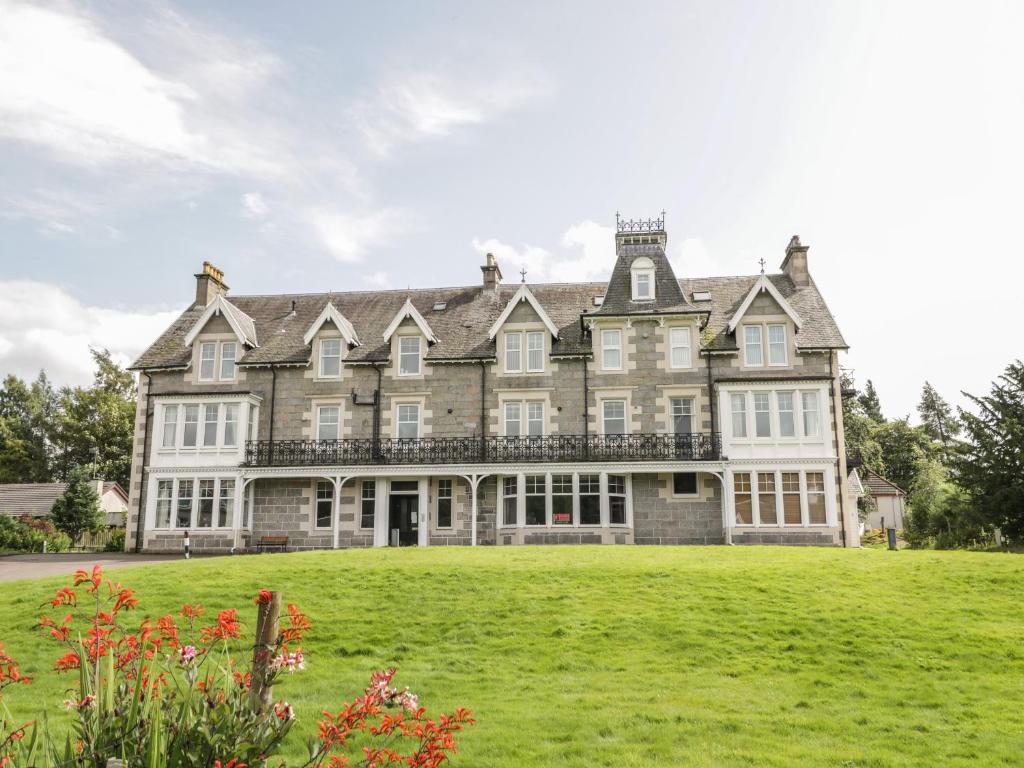 uma casa grande com um grande relvado em frente em 10 Monarch Country Apartments em Newtonmore