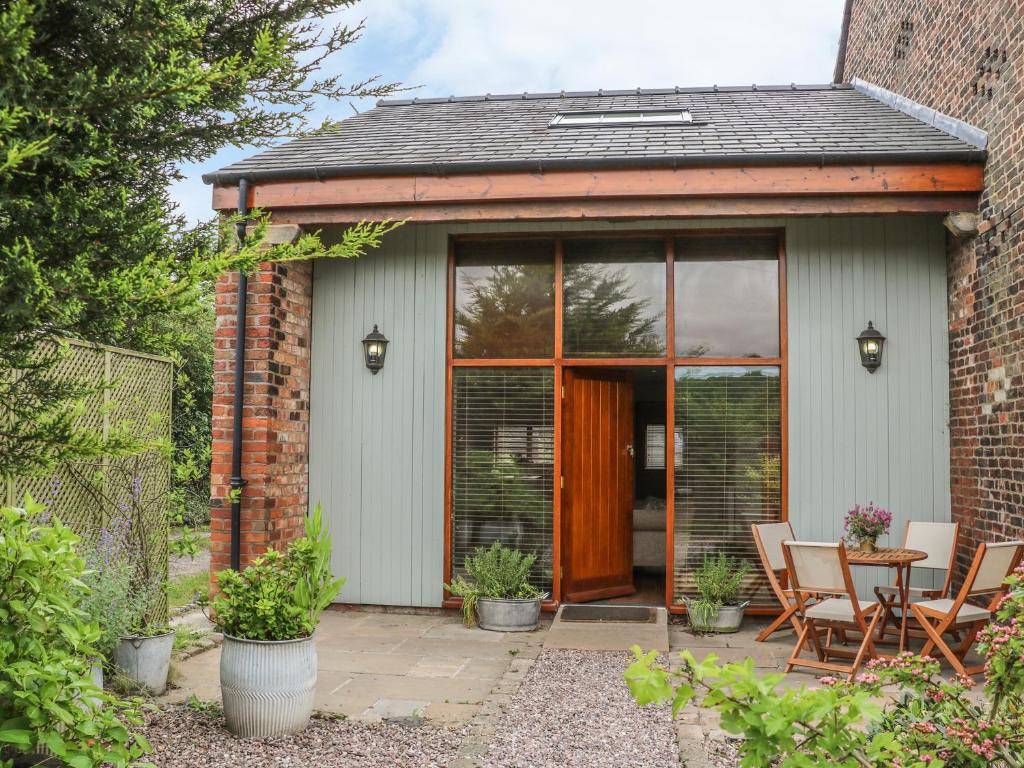 a house with glass doors and a patio at Barn Owl Cottage At Crook Hall Farm in Mawdesley