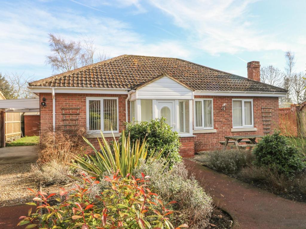 une maison en briques rouges avec des fenêtres et des buissons blancs dans l'établissement Old Orchard Cottage, à Barmby on the Moor