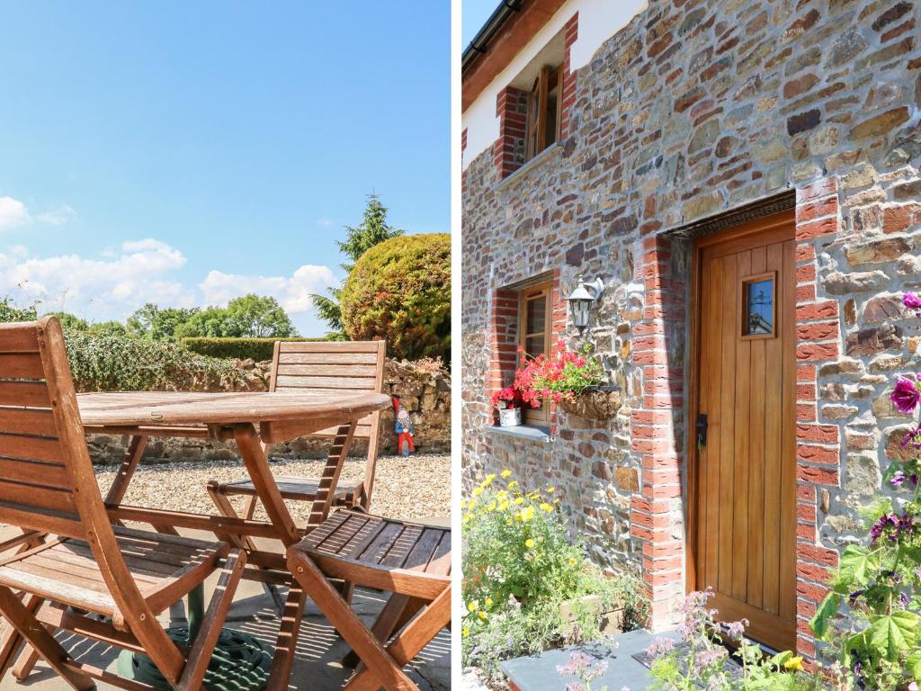 a wooden table and chair next to a brick building at Lundy View Cottage in Great Torrington