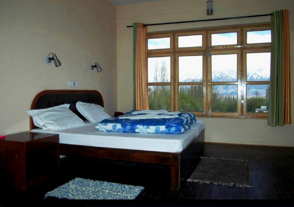 a bedroom with a bed with a large window at Hotel Ladakh Heaven in Leh