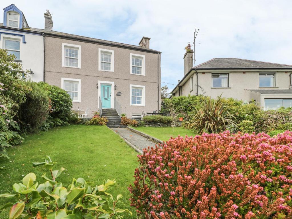 una casa grande con un patio con flores en Garth Craig, en Porthmadog