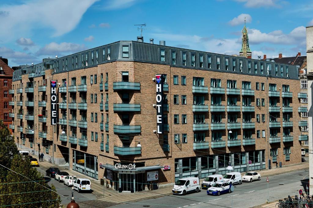 un gran edificio de ladrillo con coches aparcados en un aparcamiento en Cabinn City en Copenhague