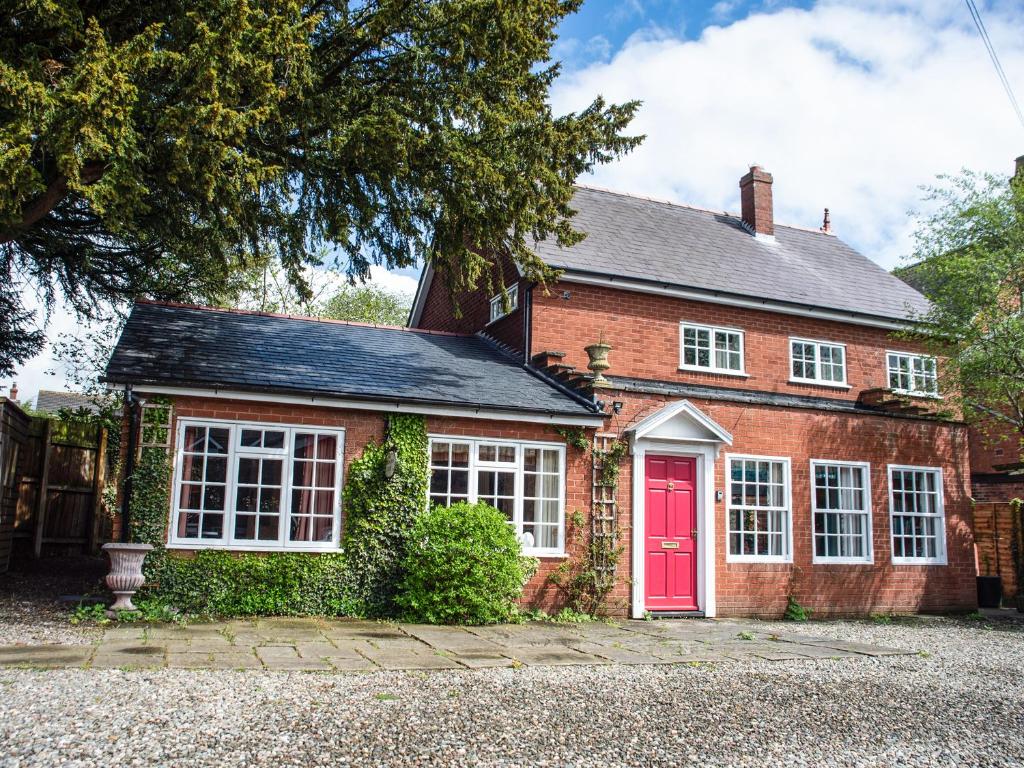 a red brick house with a red door at Dorrington Court in Dorrington