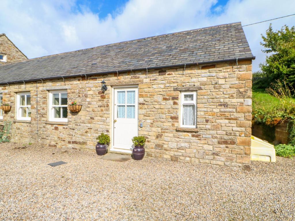 a stone cottage with potted plants in front of it at The Byre at High Watch in Lanehead