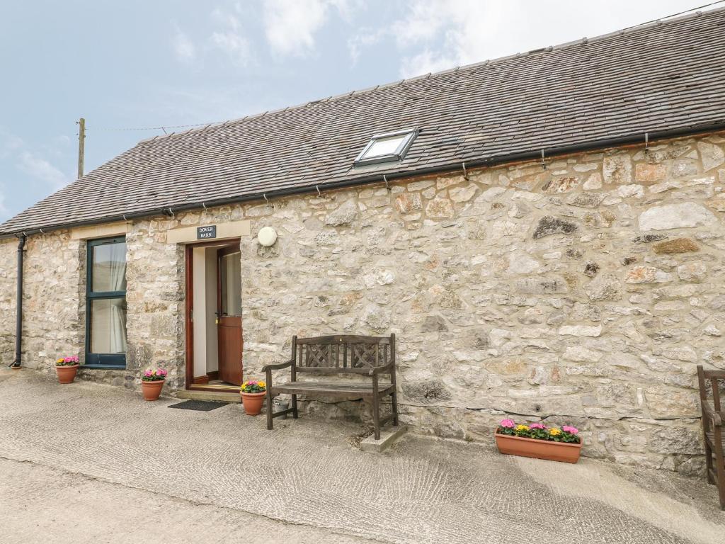 un bâtiment en pierre avec un banc devant lui dans l'établissement Dover Barn, à Parwich