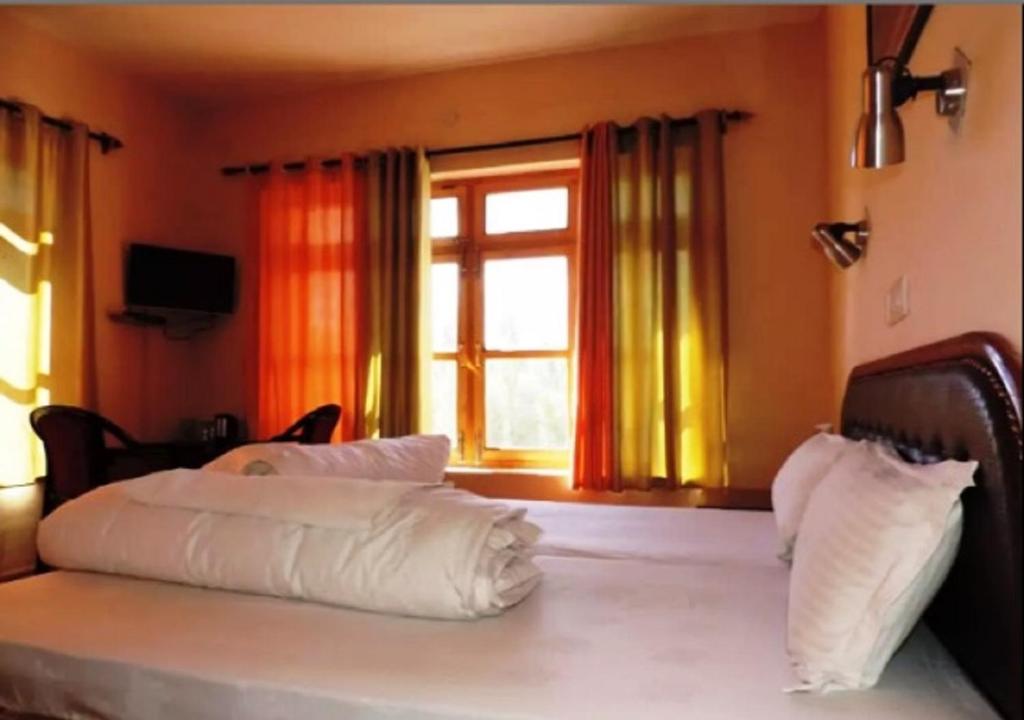 a bed with white pillows in a room with a window at Hotel Ladakh Heaven in Leh