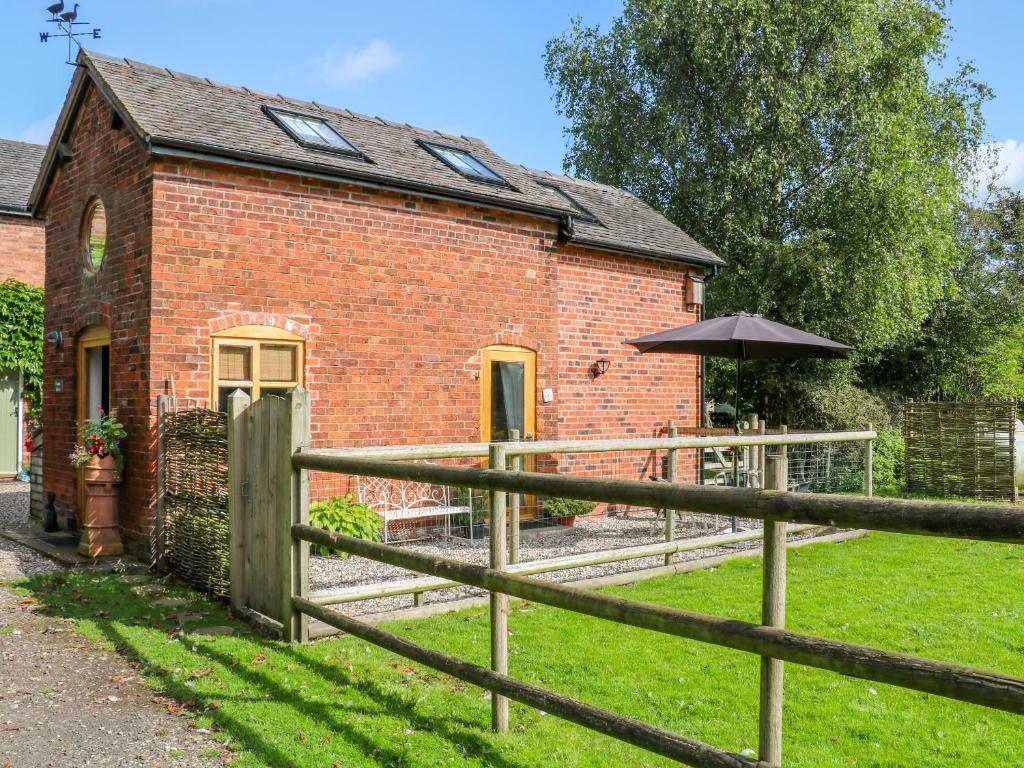 a brick house with a fence and an umbrella at Chequer Stable in Brereton cum Smethwick