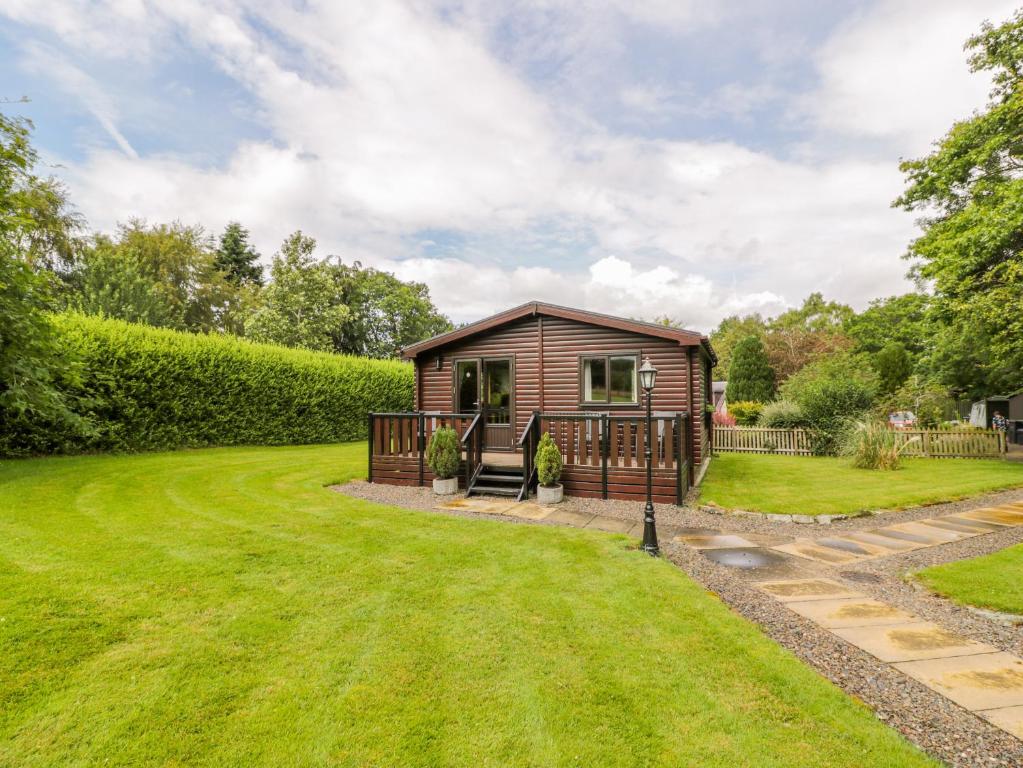 a small cabin in a garden with a grass yard at The Spinney Lodge in Jedburgh