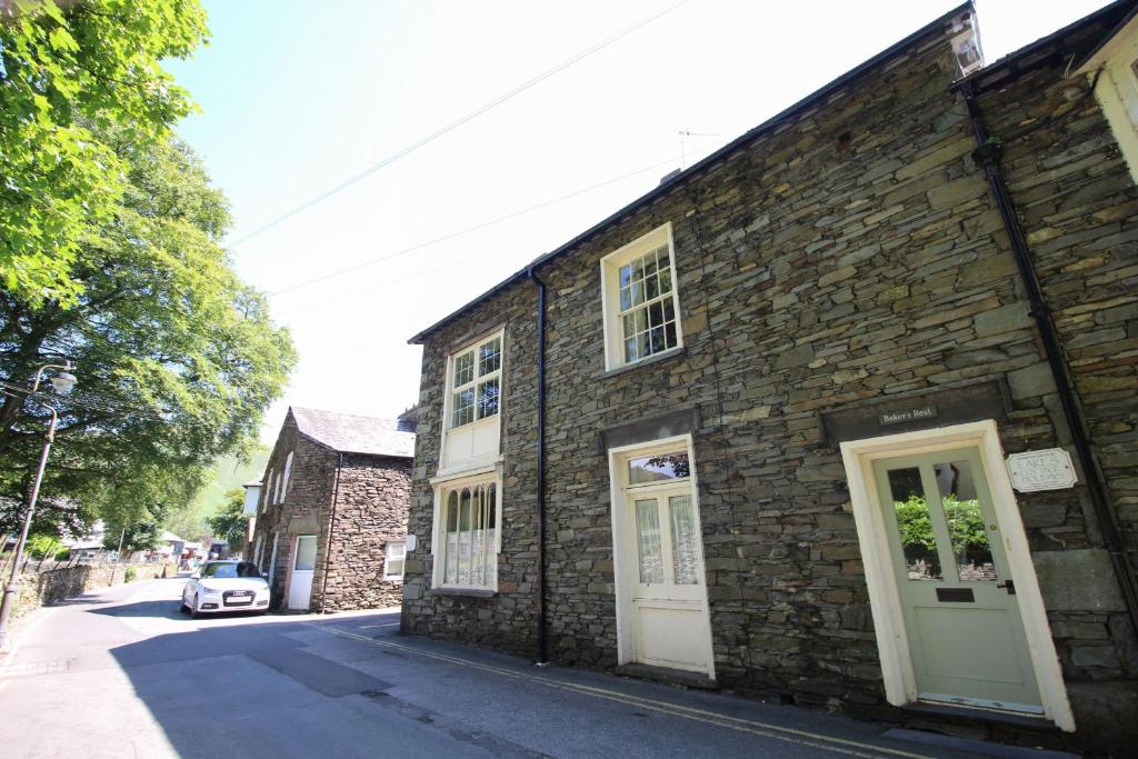 a brick building with white doors on a street at Bakers Rest ideal for 2 families centrally located in Grasmere with walks from the door in Grasmere