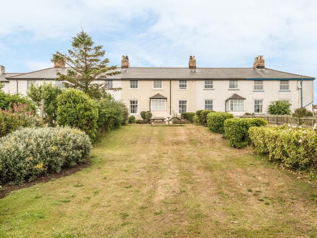 an exterior view of a large white house with a yard at 3B Coastguard Cottages in Embleton