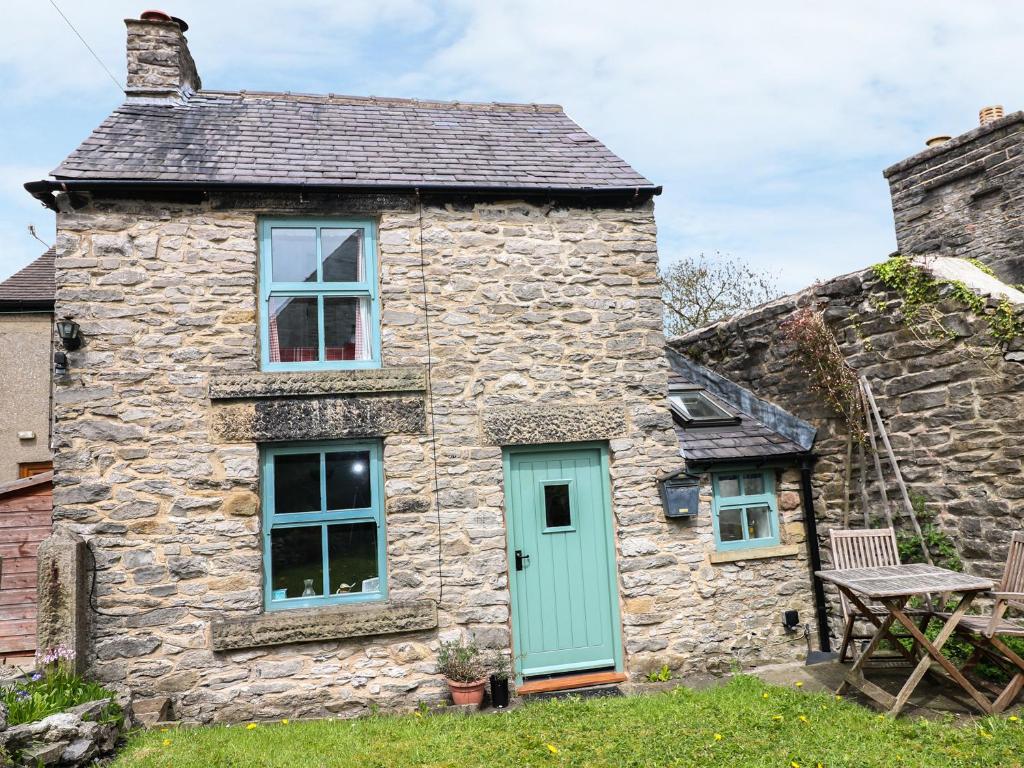 a stone cottage with a blue door and windows at Sunny Bank View in Bradwell