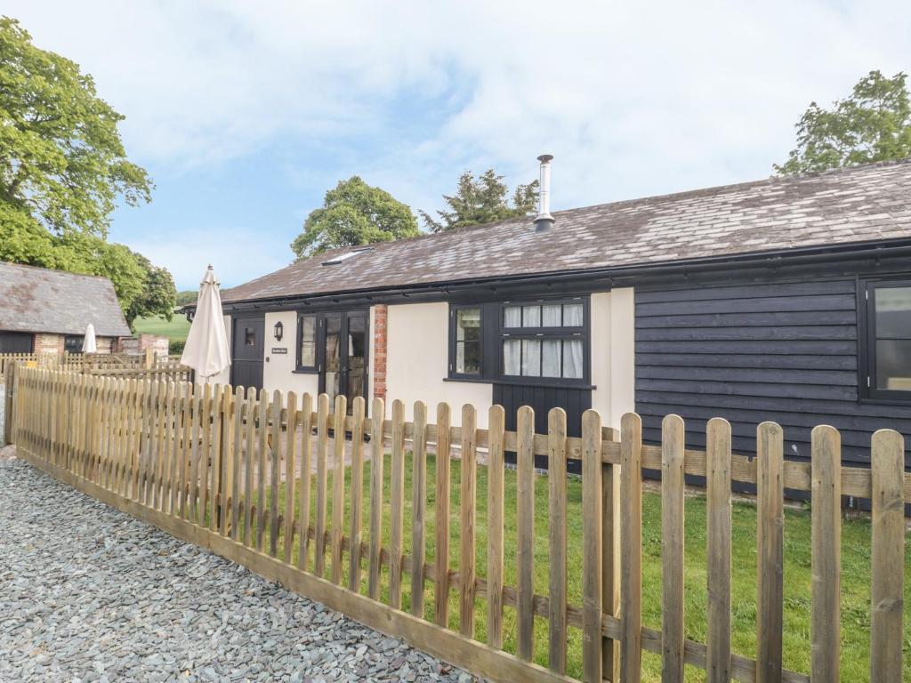 uma casa a preto e branco com uma cerca de madeira em Rowdens Barn em Winterborne Stickland
