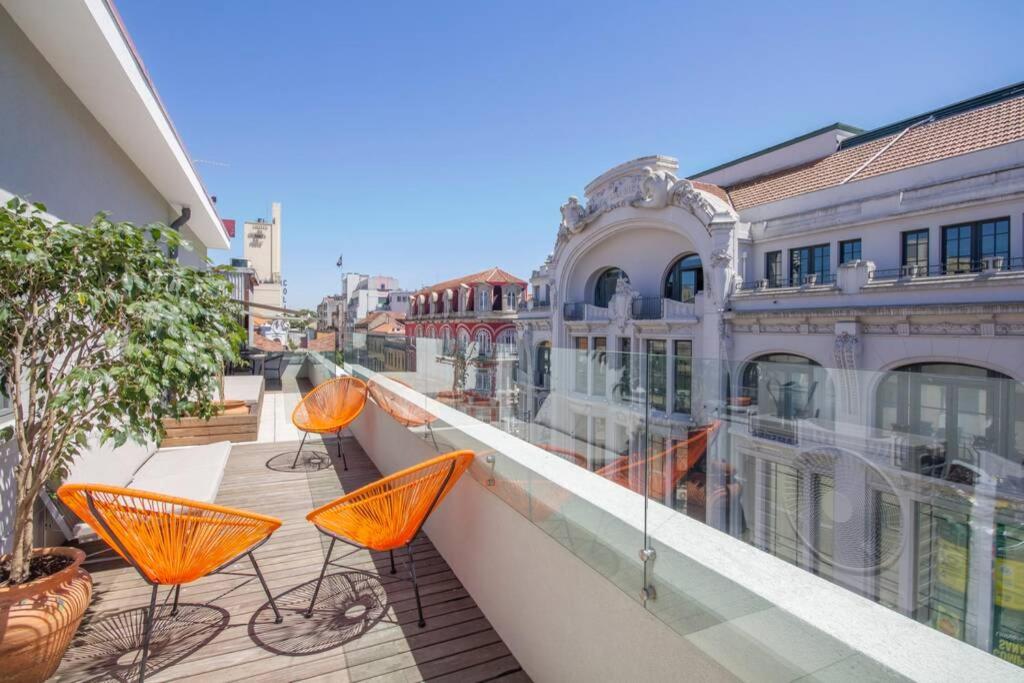 Un balcón con mesas de naranja y sillas en un edificio en Santa Catarina Roof Top, en Oporto