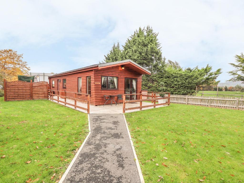 a log cabin in a yard with a grass field at Fallows in St Asaph