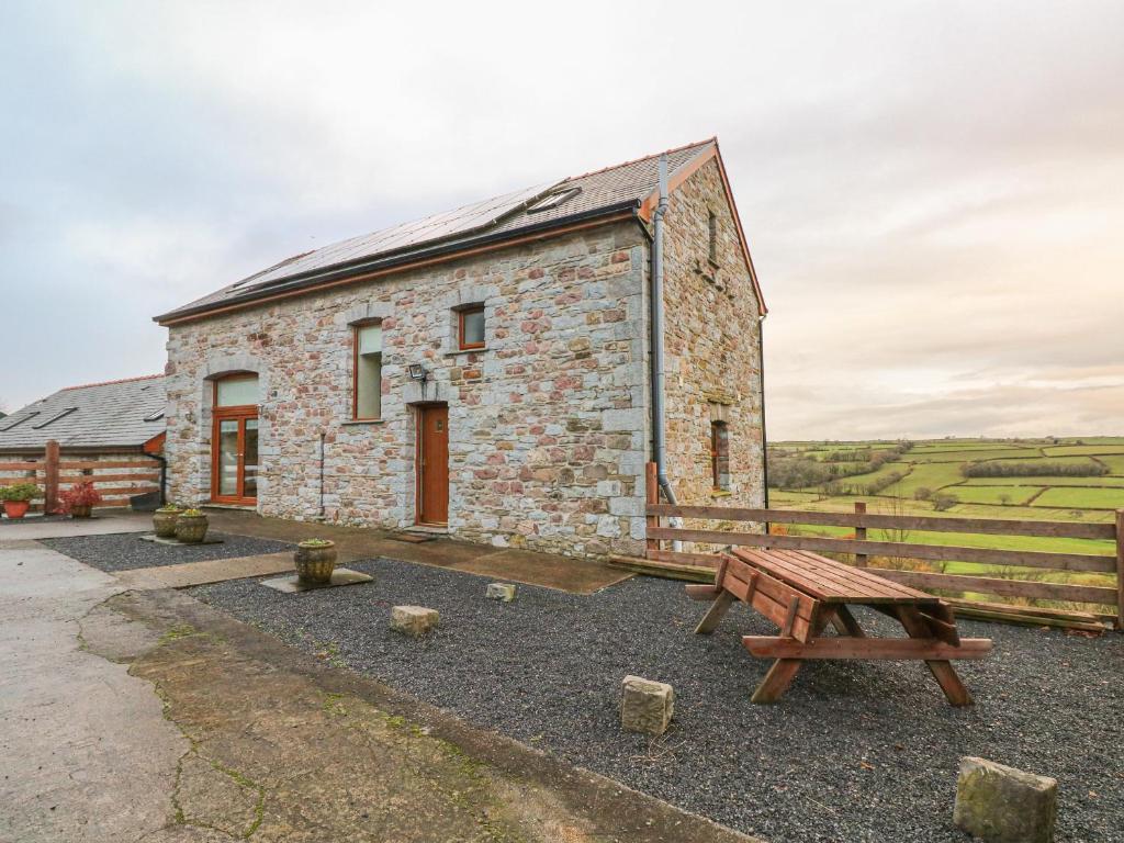 a stone building with a wooden bench next to it at Cambriol in Llangendeirne