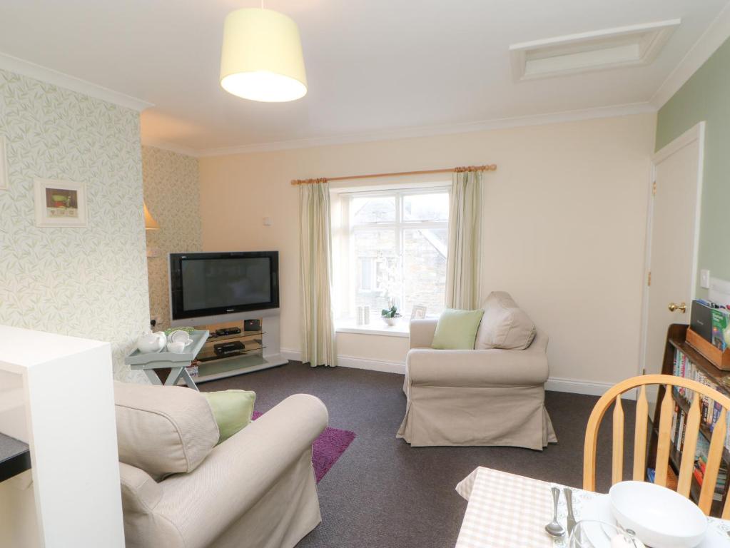 a living room with two chairs and a television at Old Queen's Head in Wolsingham