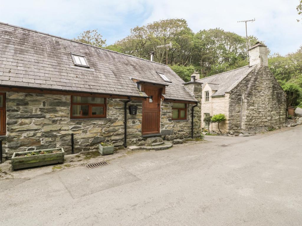 an old stone house with a driveway in front of it at Hendoll Cottage 1 in Fairbourne