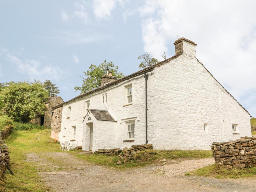 an old white cottage with a stone wall at Scale Gill Foot in Newby Head