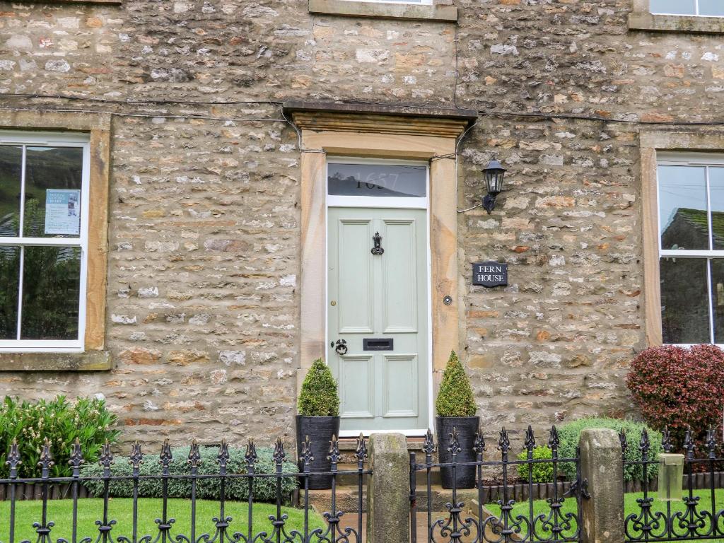 a stone house with a white door and windows at Fern House in Kettlewell